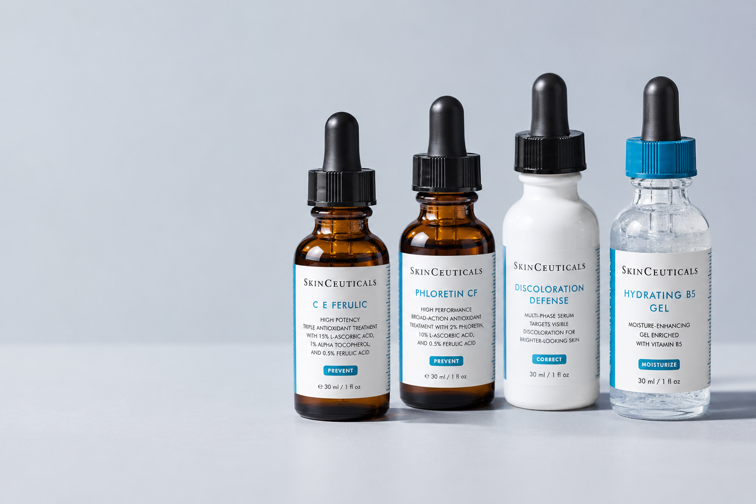 Four SkinCeuticals serums on a pale grey surface: C E Ferulic, Phloretin CF, Discoloration Defense and Hydrating B5 Gel